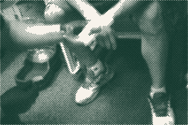 A clinic volunteer bandaging a patient&rsquo;s hand.